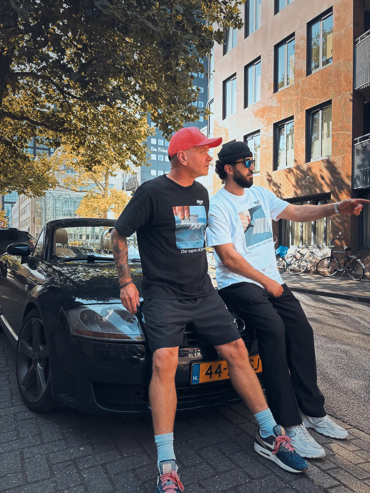 Twee mannen leunen tegen een zwarte cabrio.