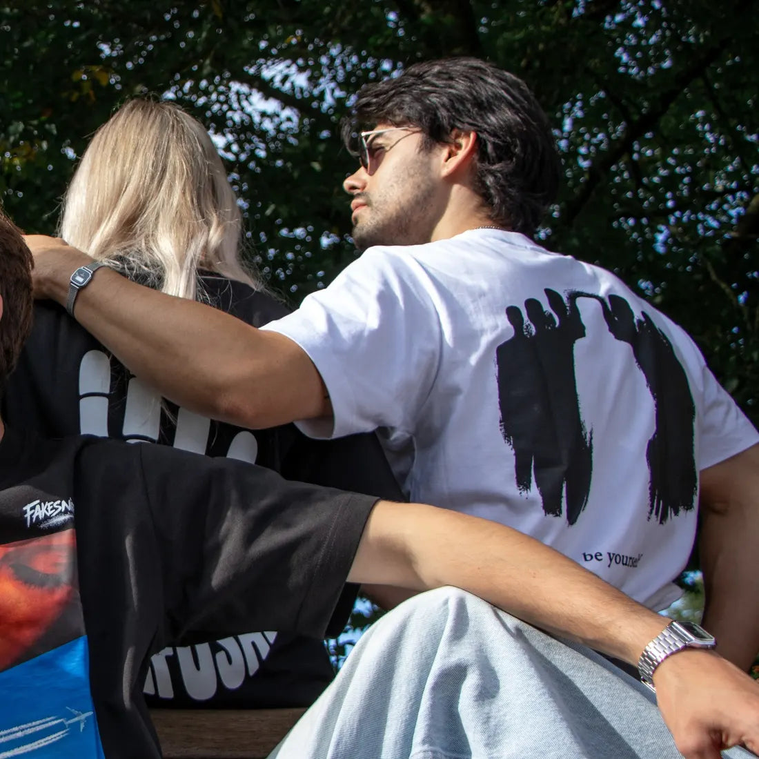 Een man op een bank met het shirt op zijn rug, zijn arm om een vriendin.