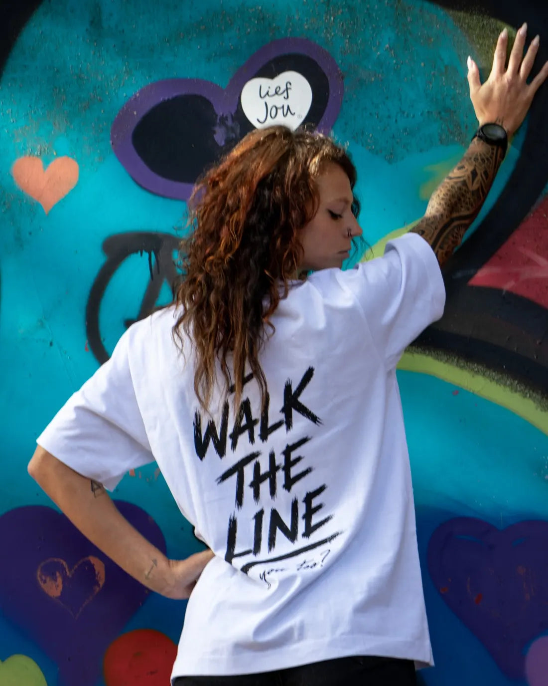 A woman with her hand against a graffiti wall.