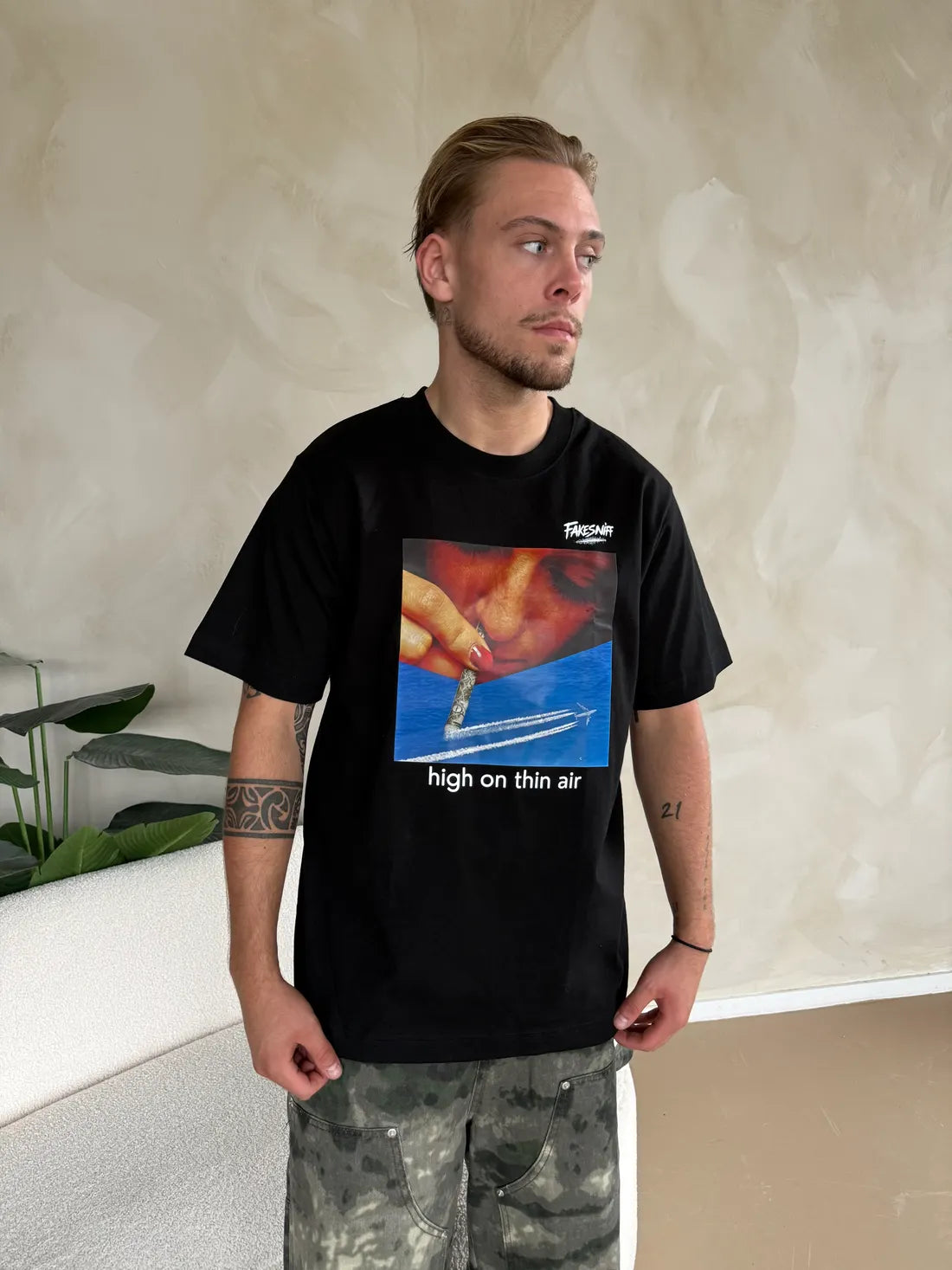 Een man in High on Thin Air zwart voor een lichte muur.