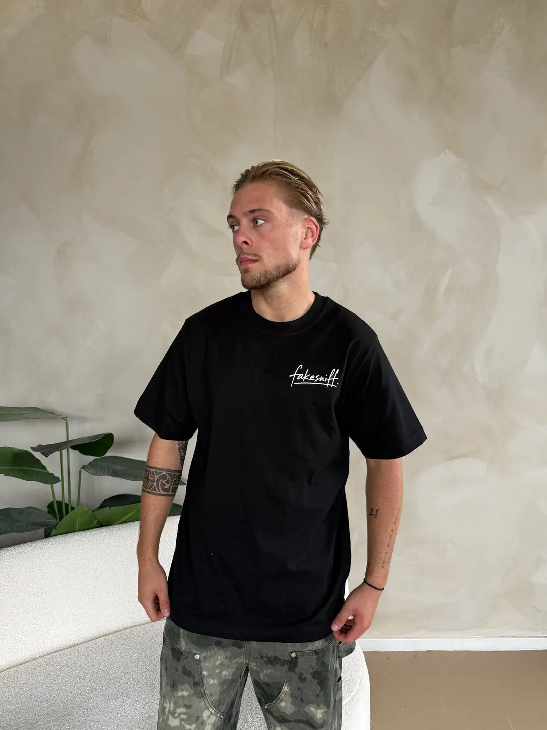 Een man in een zwart shirt met alleen het kleine logo op de borst.